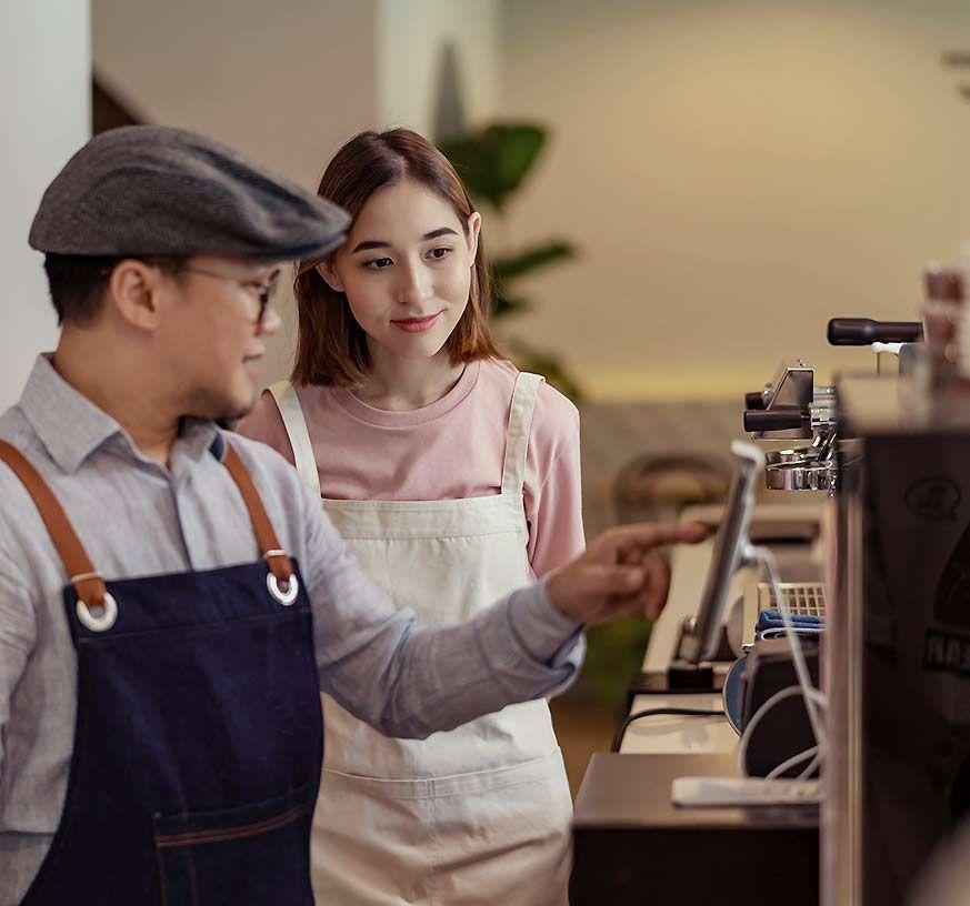 A man and woman in front of the espresso machine